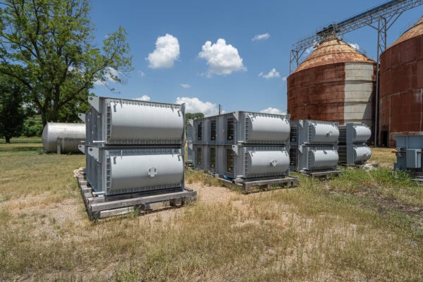 A group of metal tanks sitting in a field.